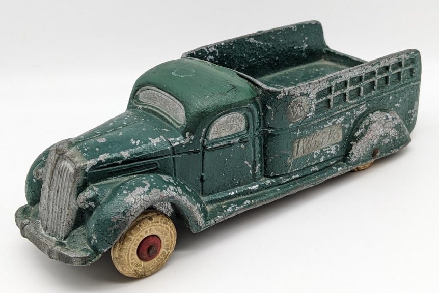 National Products White Stake Truck Promo Car: National Products White stakebed truck promo. The roof of the cab has been repainted. The truck has cracking, paint loss, and wear from age. The bed advertises Hidalgo White Truck Company, 1544 Texas 