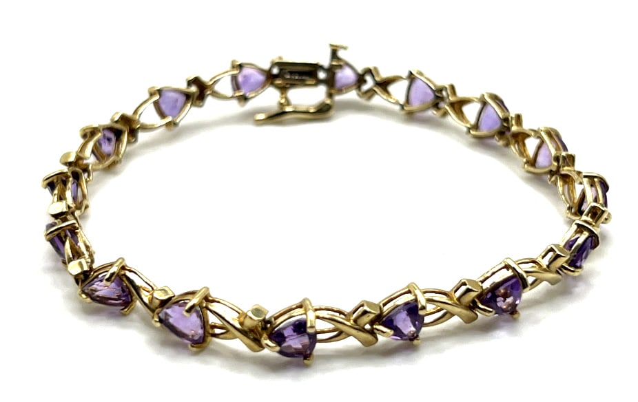 10K Yellow Gold and Amethyst Tennis Bracelet: 10K Yellow Gold and Amethyst Tennis Bracelet. This Bracelet Features Triangular Cut Amethyst Gemstones. It Has A Side Lock Clasp and Measures 7" With A Total Wt. Of 7.58 G.