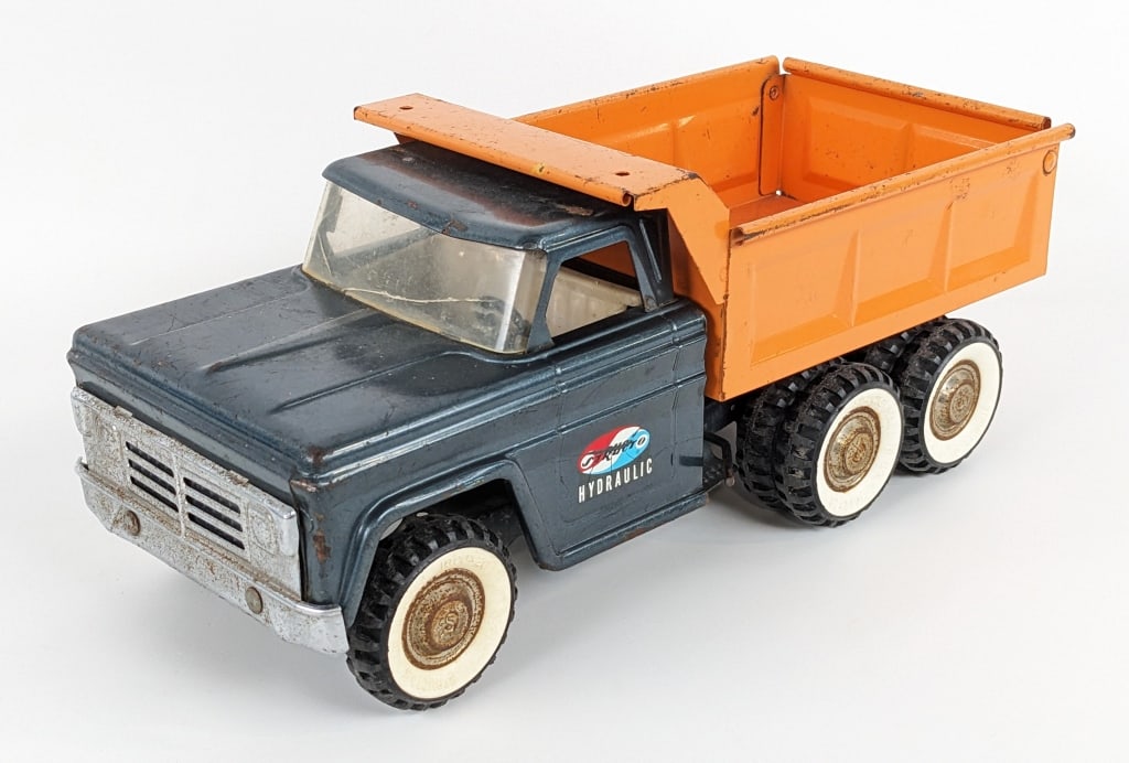 Original Structo Hydraulic Dump Truck: Original Structo hydrualic dump truck. The hydraulic dump works. The truck has damage to the windshield, surface rust, and wear from play / age. Measures approximately 14" long.