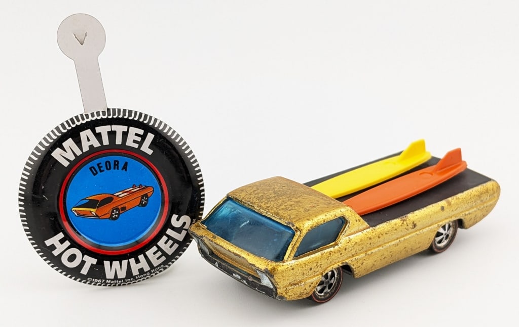 Hot Wheels Redline Hong Kong Gold Deora: Hot Wheels Redline gold Deora with brown interior. It comes with a yellow and orange surfboard. The car has toning, small knicks, and age wear. Comes with a clean metal Deora button.