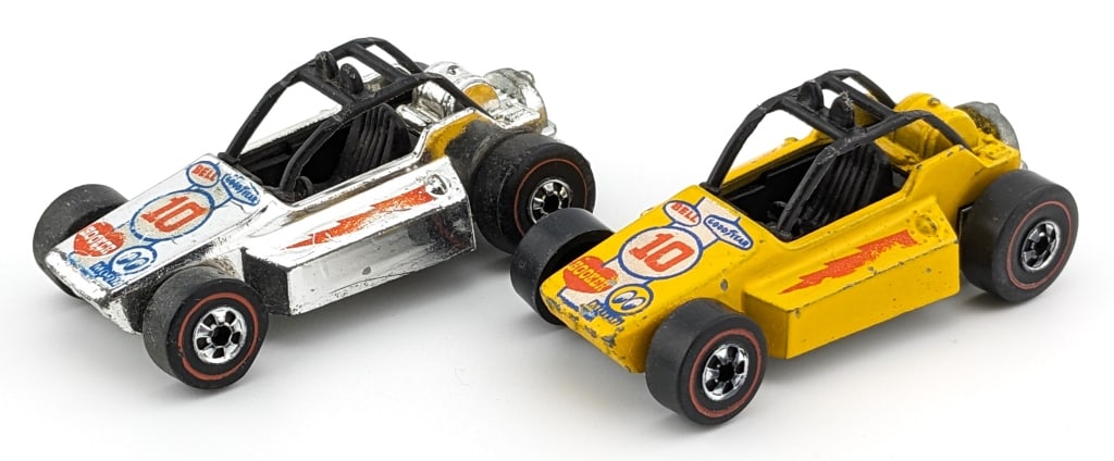 (2) Hot Wheels Redline Flying Colors Rock Busters: Hot Wheels Redline Flying Colors Rock Busters. Lot includes a yellow that has some scattered micro chips and toning to the base. The chrome car has some fading to the decals and dullness to the base.