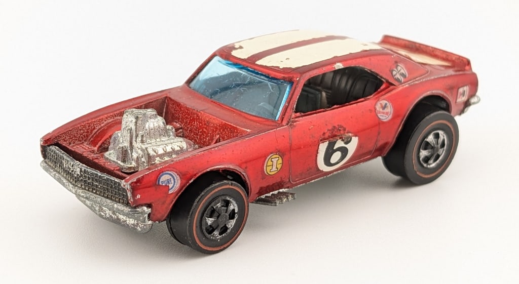 Hot Wheels Redline Red Heavy Chevy: Hot Wheels Redline red Heavy Chevy with dark interior. The car has applied sponsor decals, decal peeling to the driver side number decal, rubs to the stripes, and wear from age.