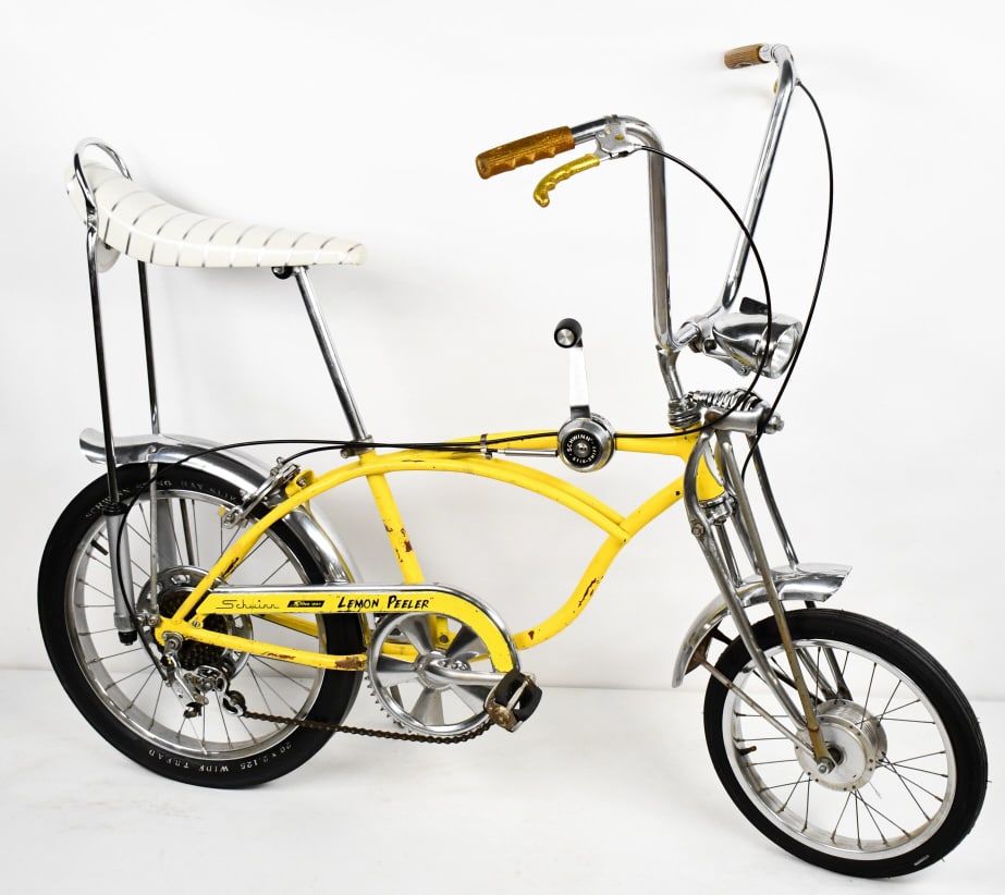 1969 Schwinn Sting-Ray Lemon Peeler Krate Bicycle: 1969 Schwinn Sting-Ray Lemon Peeler Krate Bicycle. The bike has a replaced banana seat, Schwinn 5-Speed Stik Shift, and handlebar headlight. It has paint loss, surface rust, and wear from use and age.