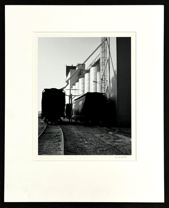 Henry Gilpin Train Cars & Silos Signed Photograph: 1982 photograph by photographer Henry E. Gilpin. The photograph is titled "Train Cars & Silos" and is in exceptional condition. Comes with the Henry Gilpin stamp on the verso and is signed in pencil.