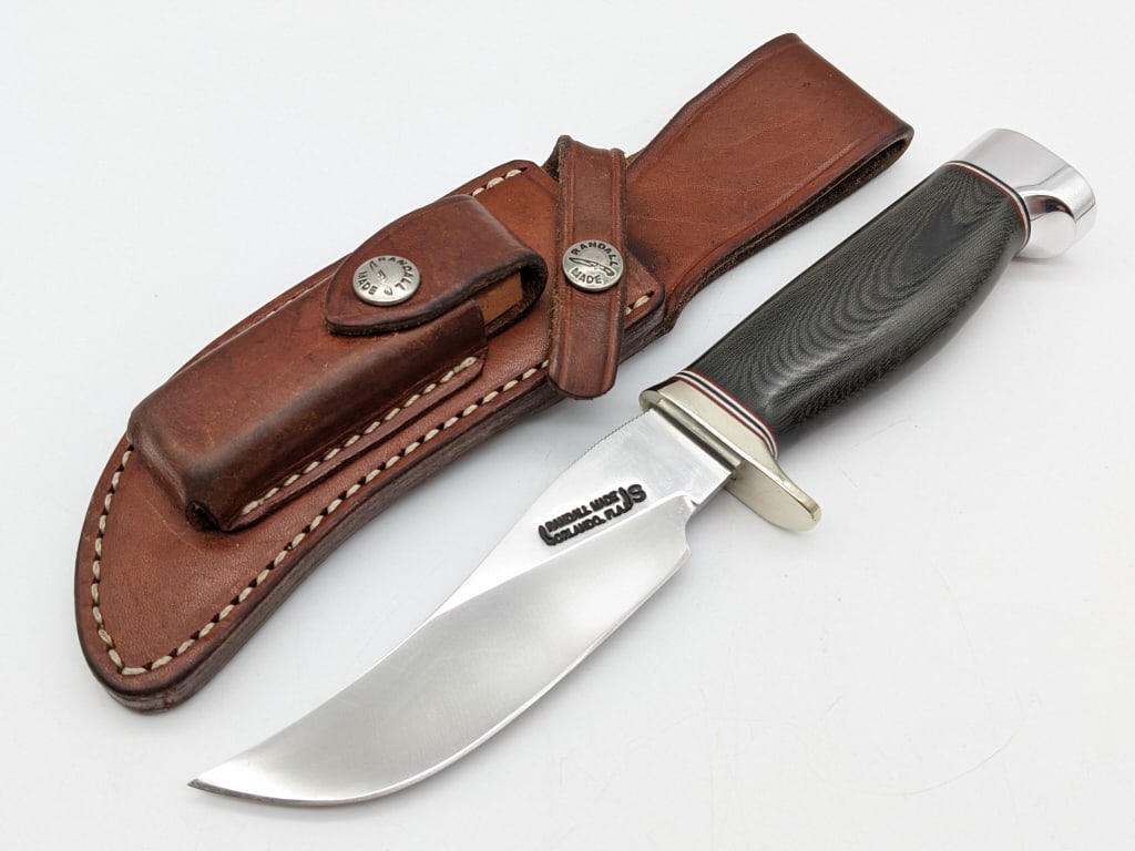 Randall Model 22 SS Micarta Outdoorsman Knife: Randall Model 22 Stainless Steel Outdoorsman Knife w/ Sheath. Knife features a stainless steel blade with thumb notches, nickel silver single downturned guard, black micarta handle, and duralumin crow