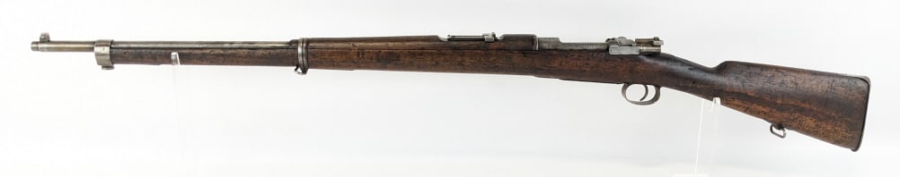Chilean Model 1895 Mauser 7mm Bolt Action Rifle: Chilean Model 1895 Mauser 7mm Bolt Action Rifle. Features a 29in barrel, bare metal finish, and smooth wood stock. Rifle is in worn condition with minimal finish left, heavy dings on the stock, a crac