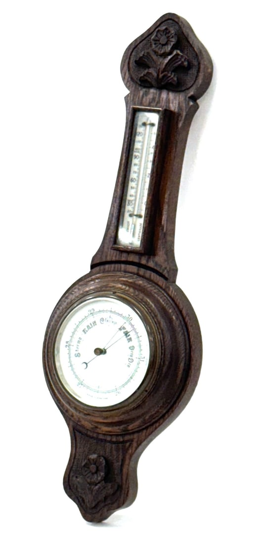 English Oak Aneroid Barometer and Thermometer: English Oak Aneroid Barometer and Thermometer. This Piece Is Of Traditional Size and Appearance. The Banjo Style Frame Is Solid and Has Flowers Carved In Relief. The Barometer Features A Porcelain Fac