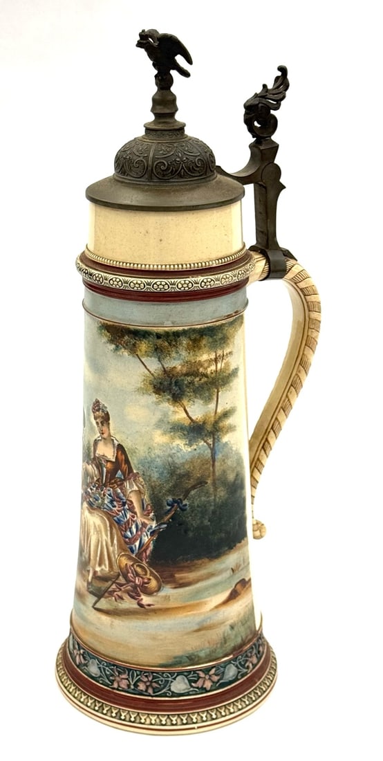 3 Liter Reinhold Hanke German Stein with Ornate Pewter Lid: 3 Liter Reinhold Hanke German Stein with Ornate Pewter Lid. A Courting Scene Is Hand Painted On The Stein with Flowers, Vines and Lines In High Relief. The Domed Pewter Lid Is Topped By An Eagle On A