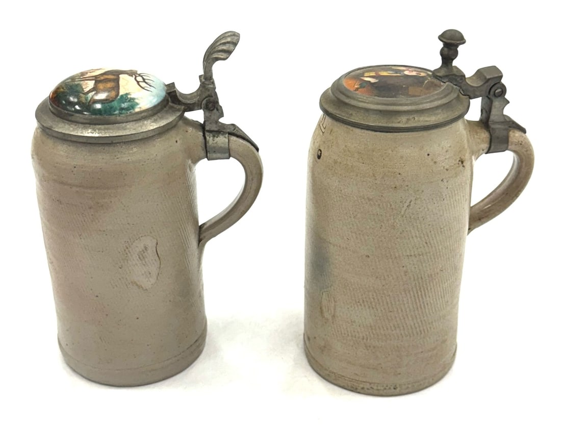 (2) Antique German Mettalach Steins with Domed Ceramic and Pewter Lids: (2) Antique German Mettalach Steins with Domed Ceramic and Pewter Lids. Thes Mettalach 1 Liter Steins That Have Hand-Painted Ceramic Lids. They Are Both In Very Good Condition For Their Age and Use. O