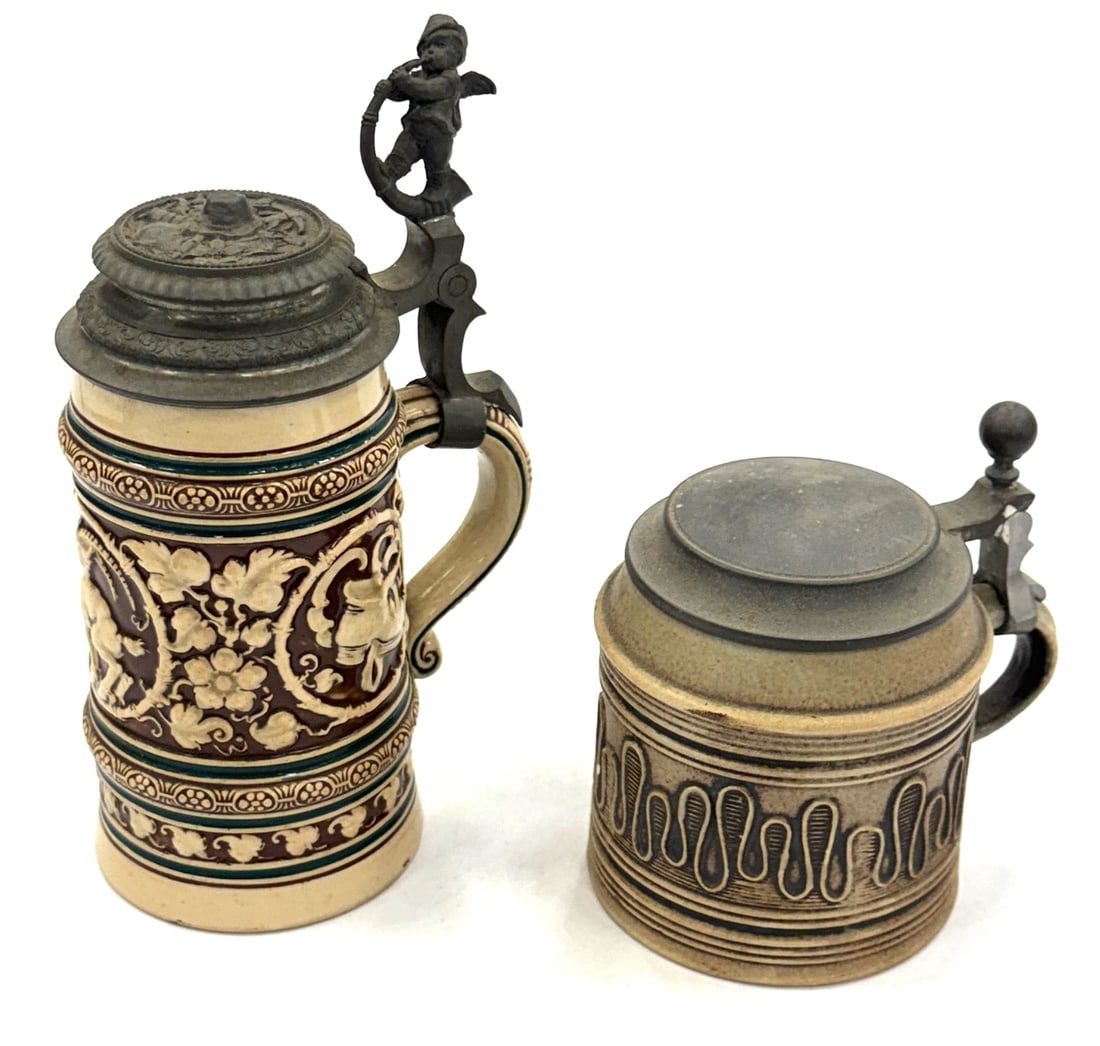 (2) German Merkelbach & Wick Steins with Pewter Lids.: (2) German Merkelbach & Wick Steins with Pewter Lids. This Set Of Steins Are In Very Good Condition. The Tallest Stein Measures 8 3/4" In Height At the Top Of The Hat-Wearing, Music Playing Cherub Tha