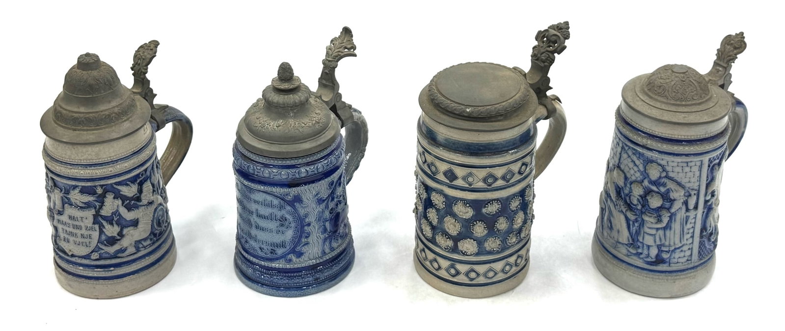 (4) German Cobalt Blue and Delft Style Salt Glaze 0.5L Steins: (4) German Cobalt Blue and Delft Style Salt Glaze 0.5L Steins. These Four Steins All Include Pewter Lids with Some Being Quite Ornate. The Bodies Of The Steins Are All In High Relief. There Are No Vis