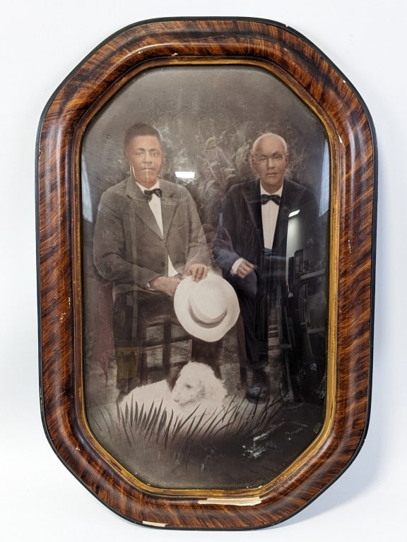 Antique Framed Photograph Of Two Black Gentlemen: Antique framed colorized photograph of two black gentlemen sitting with a dog. Photo is in good condition, frame has some nicks. Measures 20-3/8" tall x 13-3/8" across.