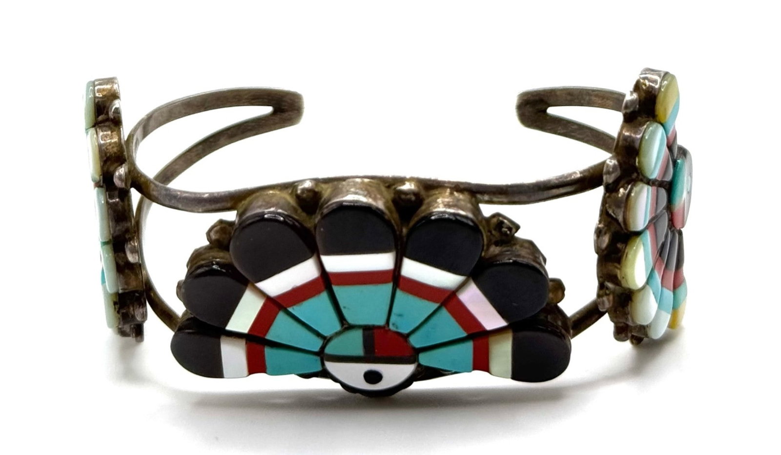 Sterling Native American Zuni Sunface Cuff: Sterling Native American Zuni Sunface Cuff Bracelet. The bracelet has multi-stones of mother-of-pearl, turquoise, onyx, and coral in the design of the Zuni's tribe symbol Sunface, which represents the