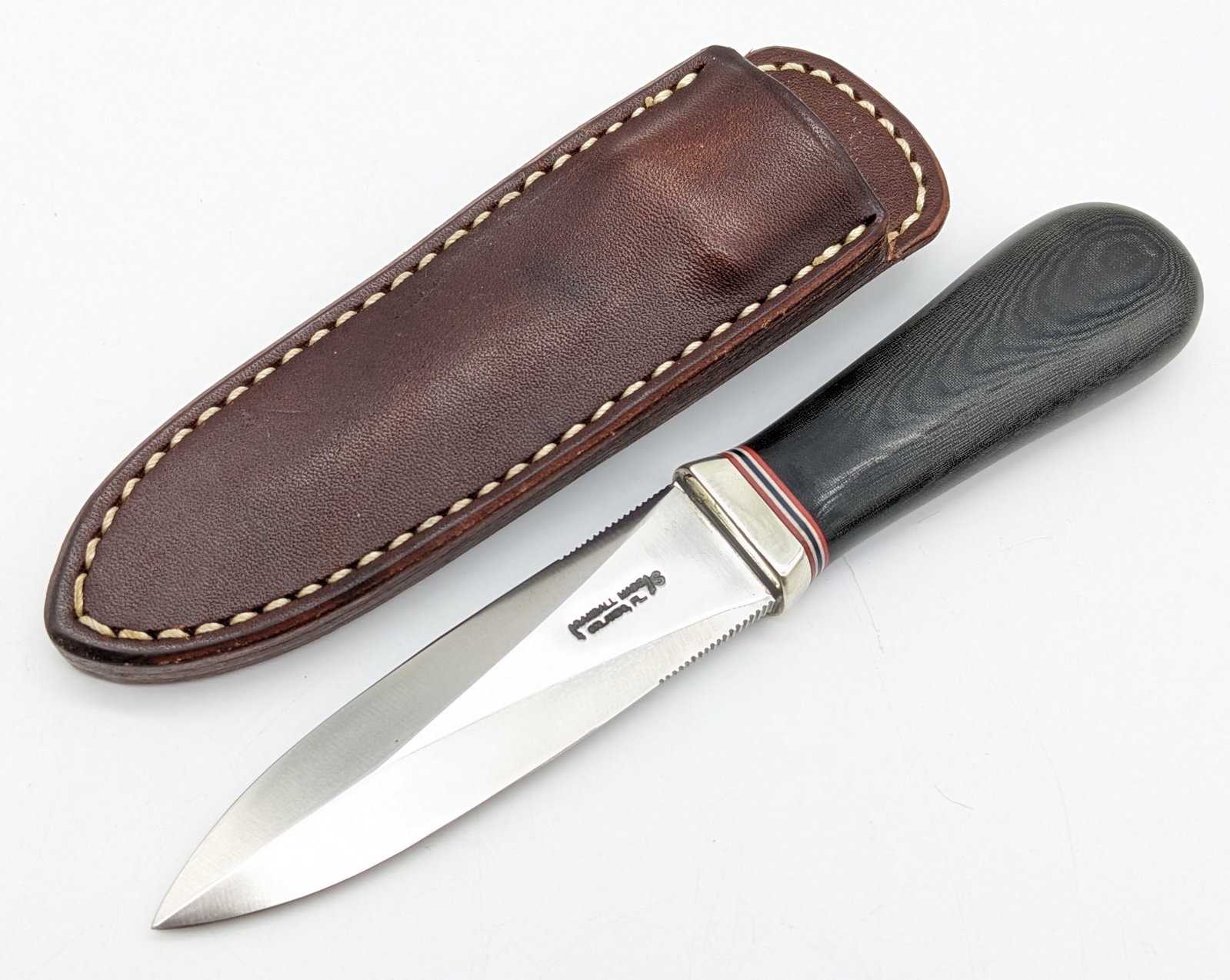 Randall Model 24 Guardian Stainless Steel Knife w/ Sheath: Knife is in like new condition. Features a stainless steel blade with thumb notches on either side, a nickel silver reduced guard, and black micarta handle. Comes with the Randall leather sheath. Blad