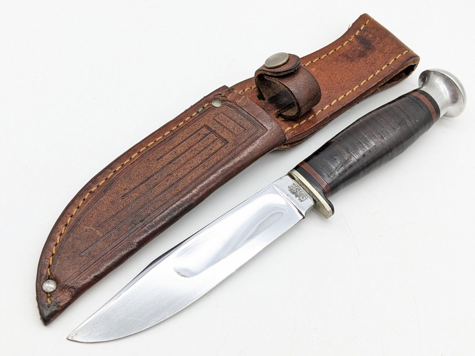 1940-65 Case XX Hunting Knife w/ Sheath: Knife features a mirror polished blade with fullers and thumb notches, small aluminum guard, stacked leather handle, and aluminum pommel. Knife is in very nice condition with light wear with light scu