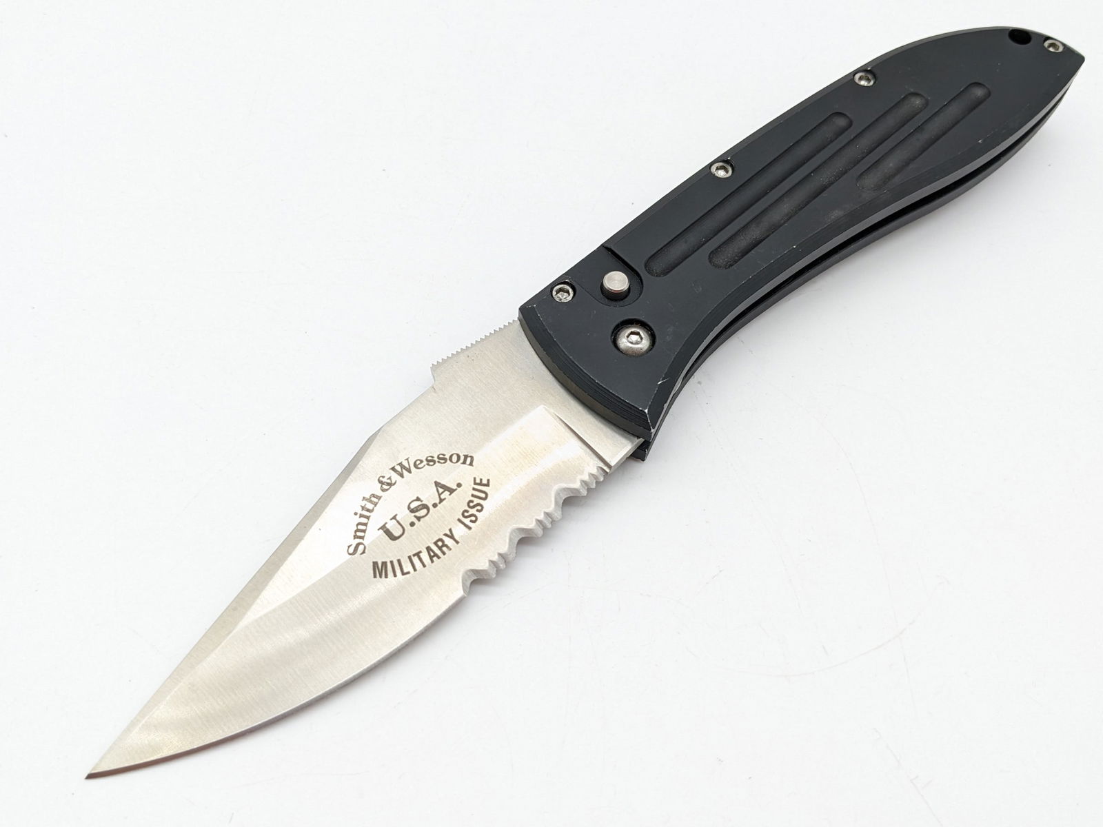 Smith & Wesson SW1000 Military Issue 1st Production Run Switchblade Auto Knife: Knife features a satin finish partially serrated blade, and fullered black anodized aluminum handle. Knife appears to be in unused condition, but has wear on the handle from carrying and handling. Ove