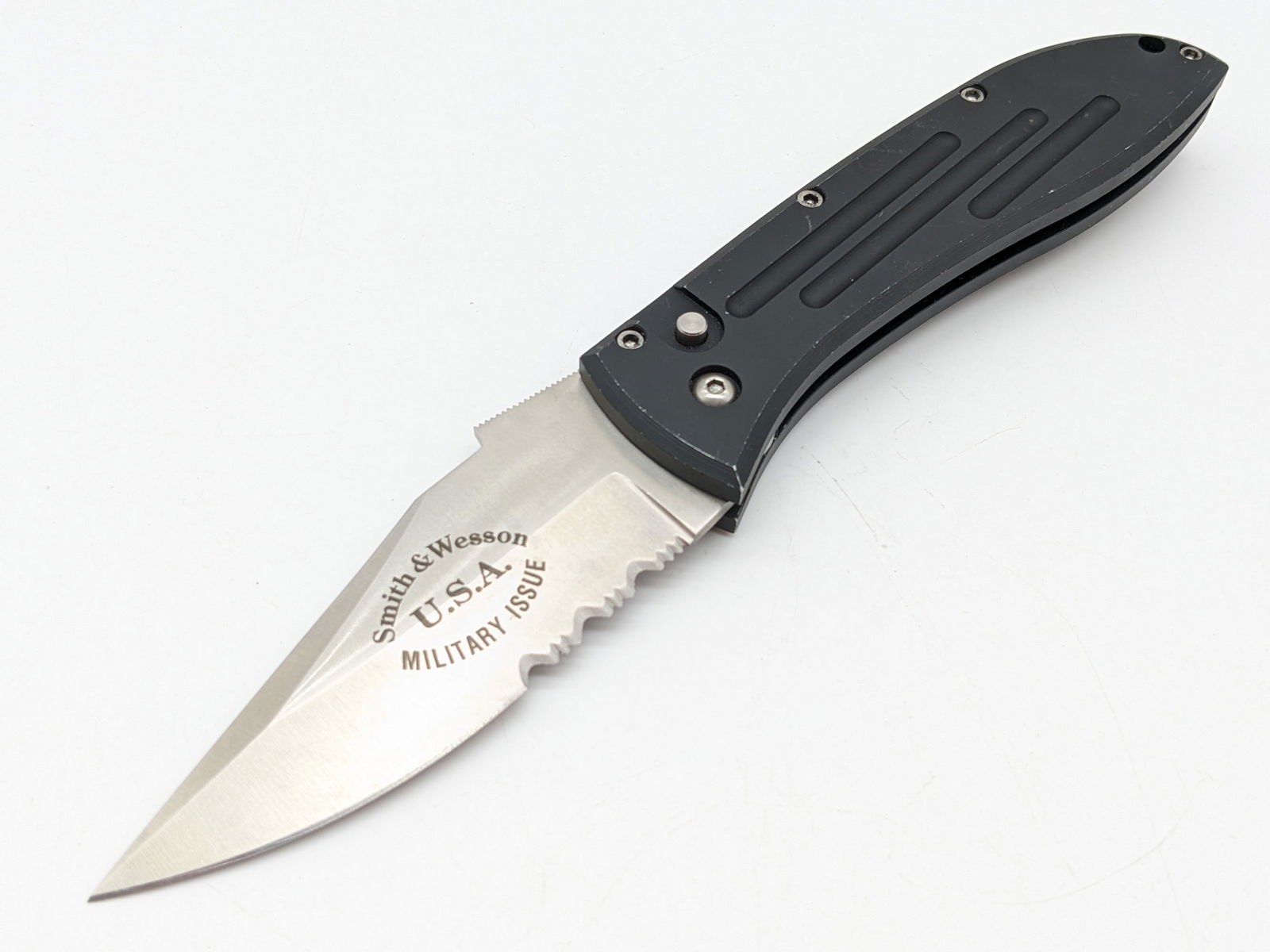 Smith & Wesson SW1000 Military Issue 1st Production Run Switchblade Auto Knife: Knife features a satin finish partially serrated blade, and fullered black anodized aluminum handle. Knife appears to be in unused condition, but has wear on the handle from carrying and handling. Ove
