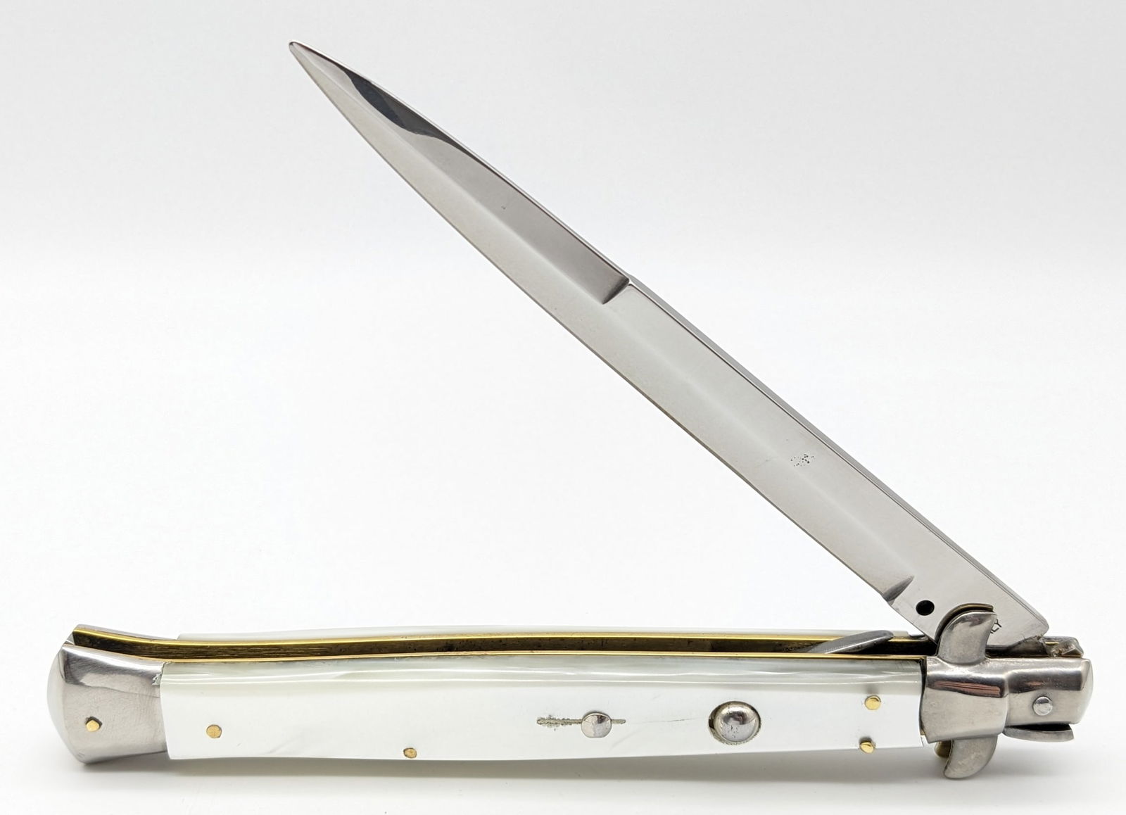 Large Maniago Italy Stiletto Switchblade Knife: Knife features a large 6in stiletto blade, swing guard locking design, and faux pearl handle scales. Knife is in very nice condition with minimal wear from handling. Overall measures 7-1/8in when clos