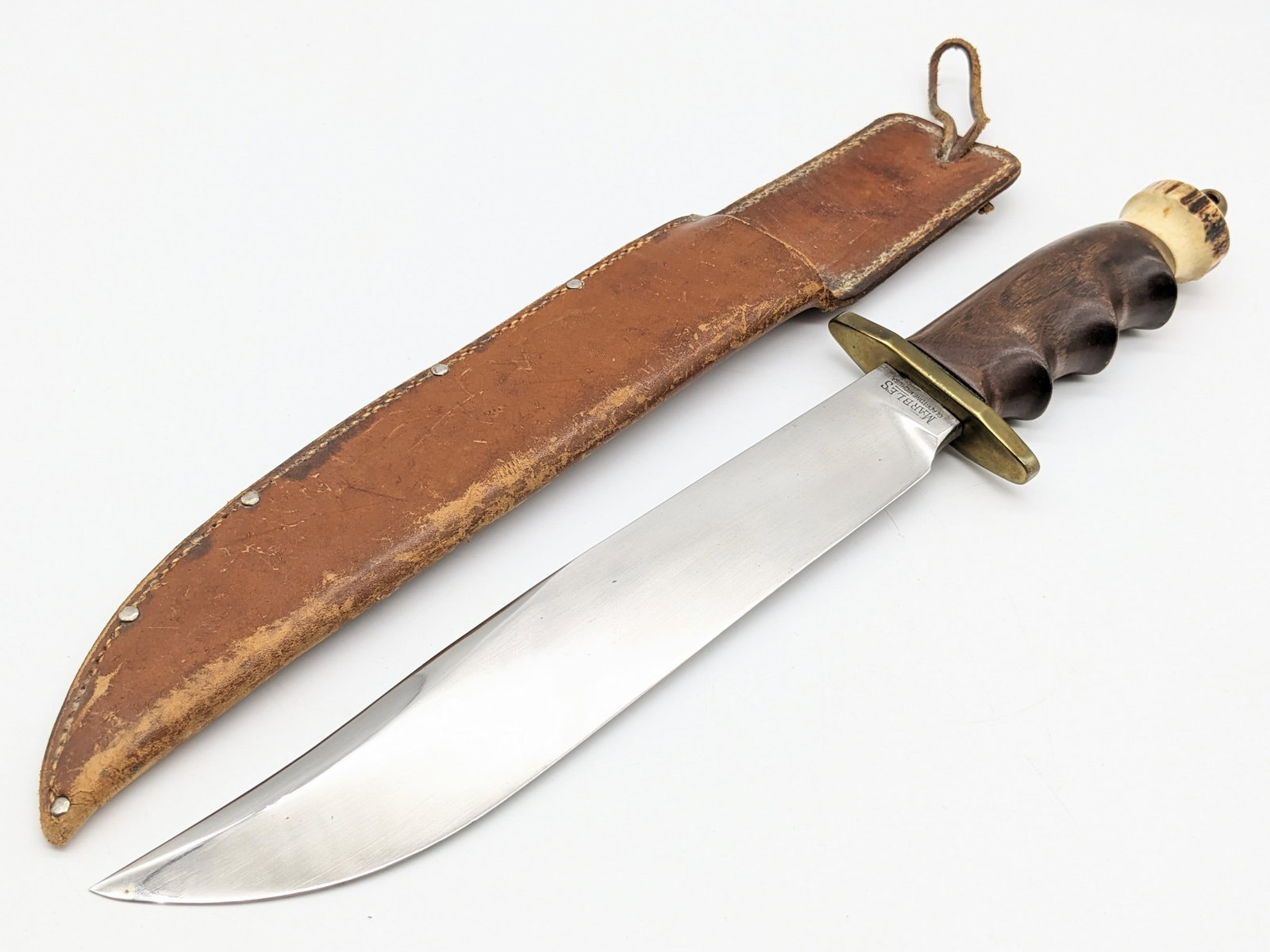 Marble's Third Model 10in Trailblazer Custom Bowie Knife w/ Sheath: Features a mirror polished clip point blade, brass oblong double guard stamped with the initials H.J.E., finger groove wood handle, and stag pommel with a brass lanyard hole. Knife is in nice custom c