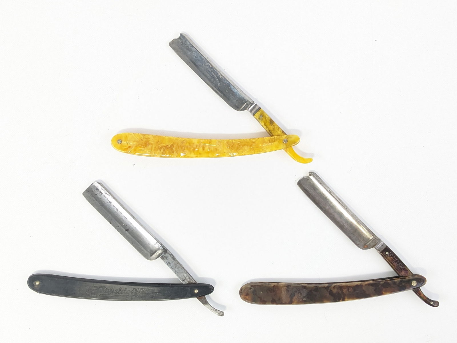 (3) Antique Robeson ShurEdge Straight Razors: Razor models include 1560, 2583, and an unmarked model. Razors features celluloid and plastic handle scales, and are in nice aged condition with carbon spotting and scuffs from use and age. Largest ov