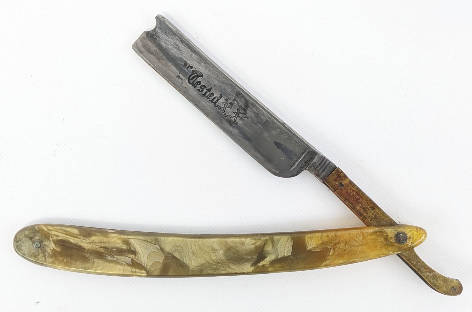 1900-32 Case Brothers Tested XX Celluloid Straight Razor: Features a celluloid handle and lower tang section. Razor is in good aged condition with carbon spotting and darkening on the blade, scuffs on the handle, and a crack on the celluloid on the tang. Ove