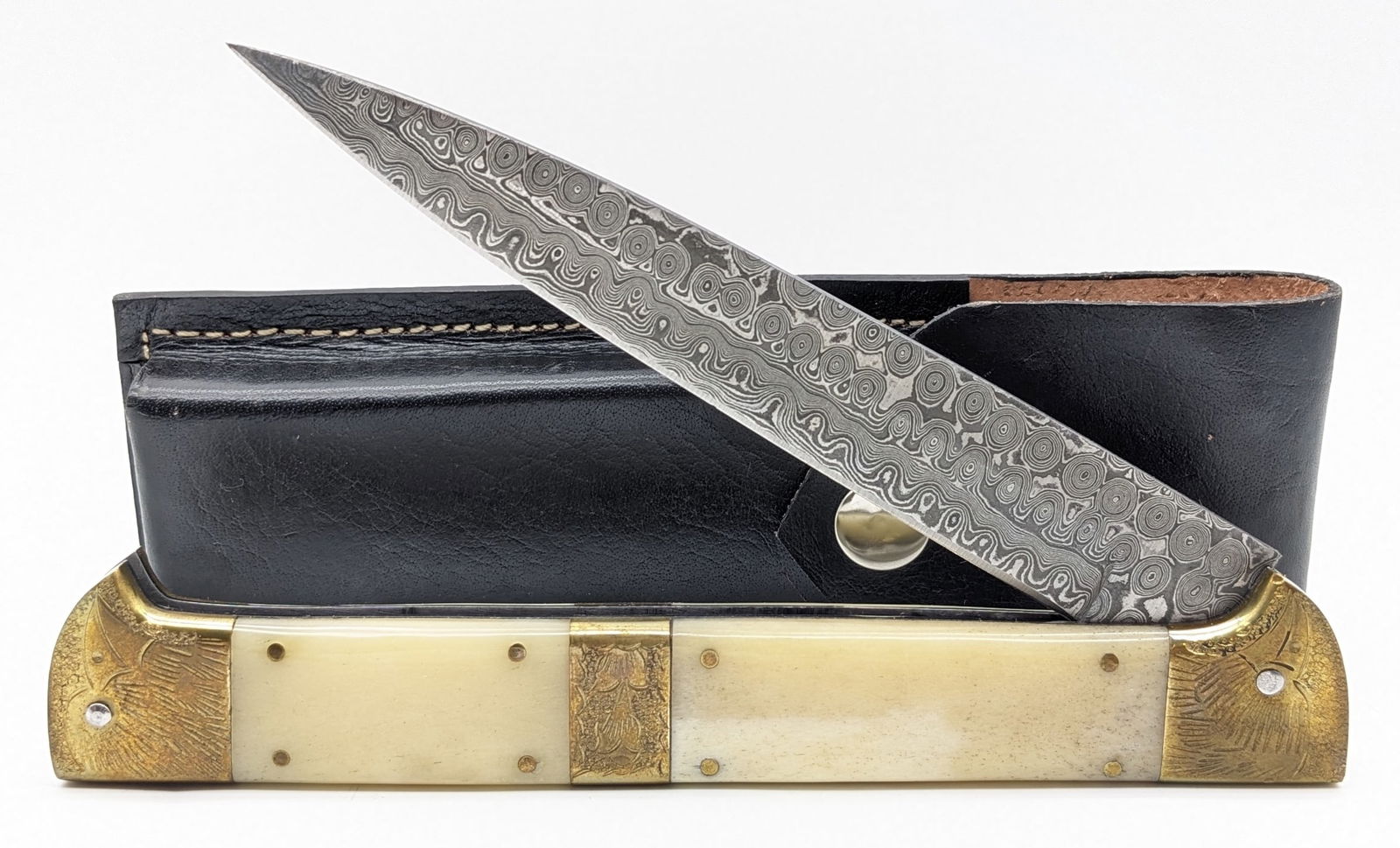 Large Engraved Smooth Bone Rain Drop Damascus Switchblade Knife w/ Sheath: Knife is in like new condition with file work along the spine, and eagle engraving on the bolsters. Overall measures 7in when closed.