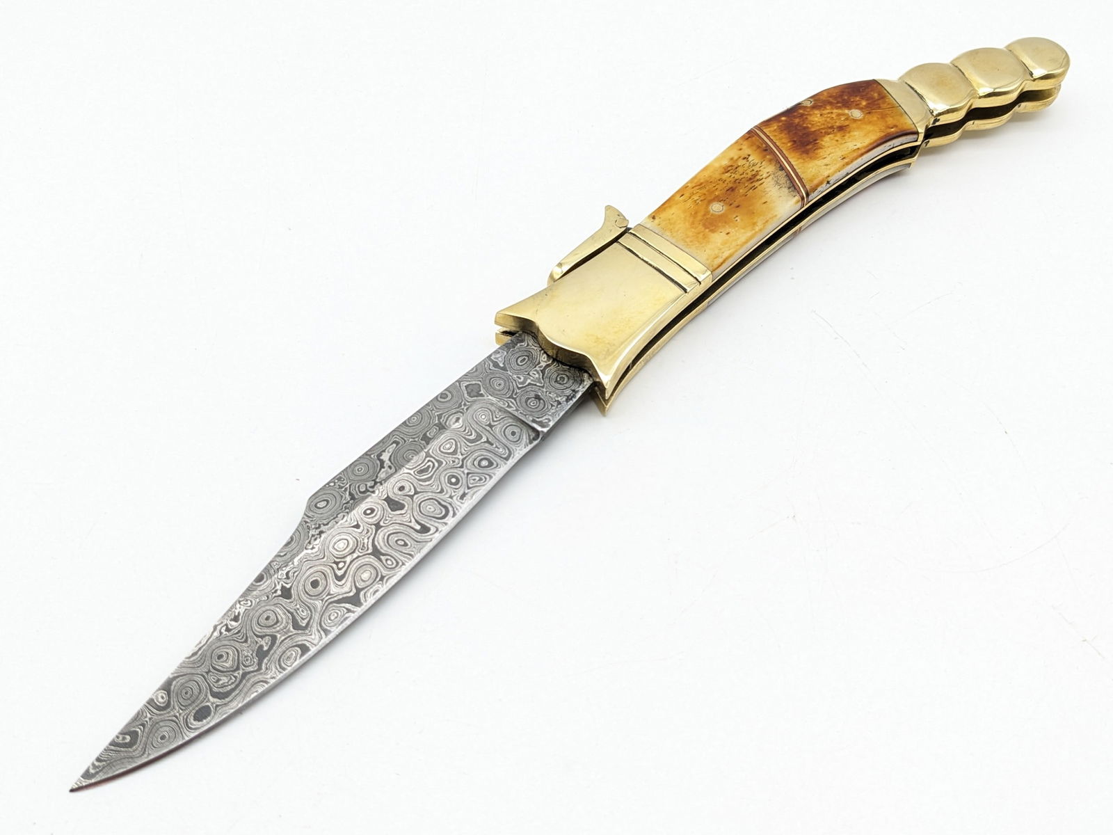 Large Smooth Bone Rattlesnake Rain Drop Damascus Leverlock Switchblade Knife: Knife features a unique rattlesnake design bolster, and nice rain drop damascus blade. Knife is in good condition with scuffs on the bolsters from handling. Knife spring is strong, and locks tight whe