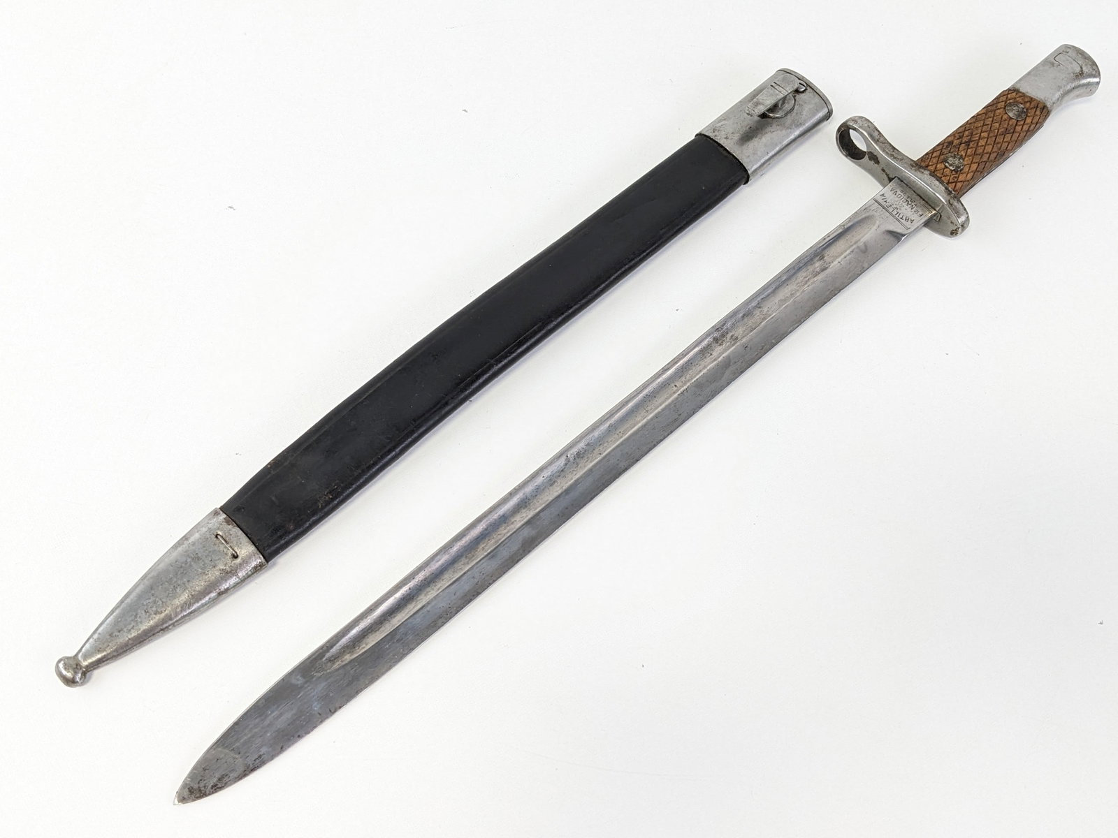 Spanish Model 1893 Artilleria Toledo Bayonet w/ Scabbard: Features a fullered blade stamped 8854B, steel guard, checkered wood handle, and steel pommel. Bayonet is in good condition with light scuffs and carbon spots on the blade, tarnishing on the guard, an
