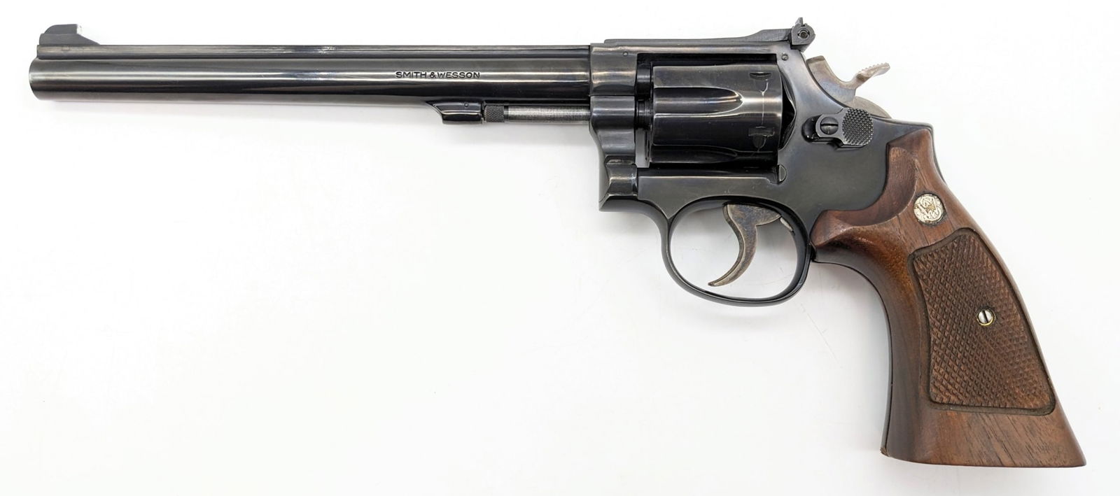 Smith & Wesson Model 17-4 .22 LR Revolver: Manufacturer: Smith & Wesson.Model: 17-4.Type: Revolver. Caliber/Gauge: .22 LR. Barrel: 8-1/4 inch. Choke: . Finish: Blued. Grip: Wood. Stock: . Condition: Nice with light scuffs and wear from use and