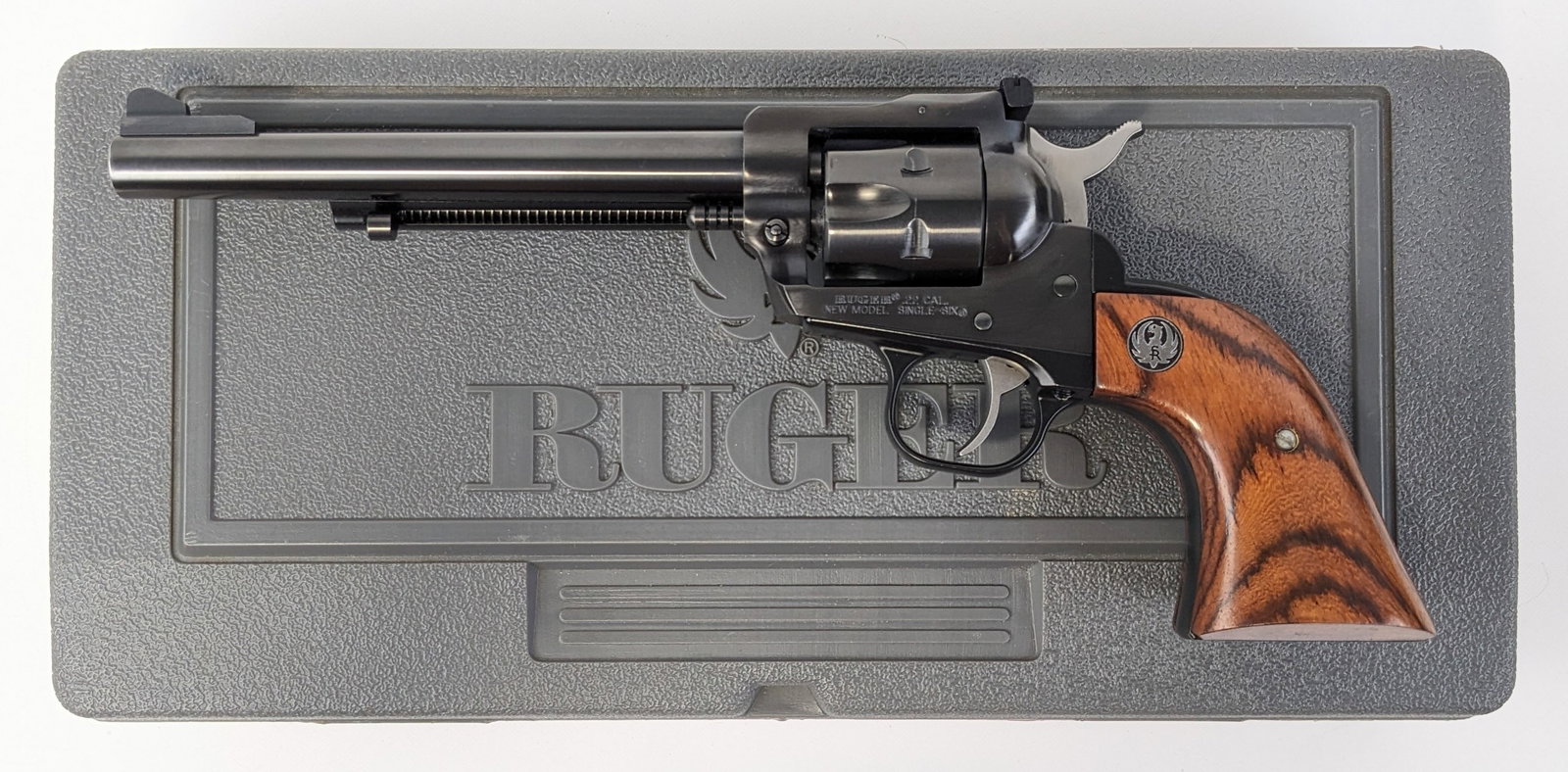 Ruger New Model Single-Six .22 Cal Revolver w/ Case: Manufacturer: Ruger.Model: New Model Single-Six.Type: Revolver. Caliber/Gauge: .22 LR / .22 WMR. Barrel: 6-1/2 inch. Choke: . Finish: Blued. Grip: Wood. Stock: . Condition: Near new with minimal wear 