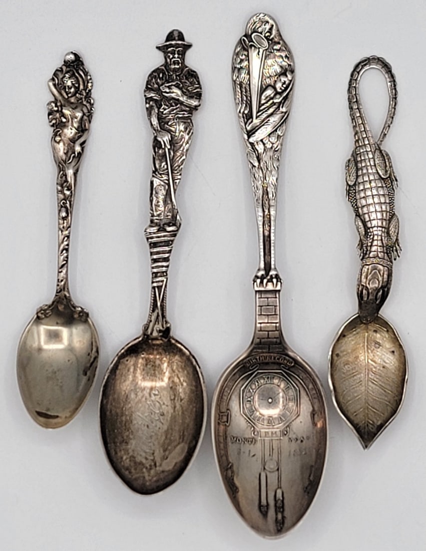 (4) Antique Figural Sterling Silver Souvenir Spoons: Spoons include a Gold Miner, Alligator, Love Disarmed, and The Stork. All are engraved and measure 4-1/4" to 5-3/4" long. Total weight 2.71 troy ounces of sterling silver.