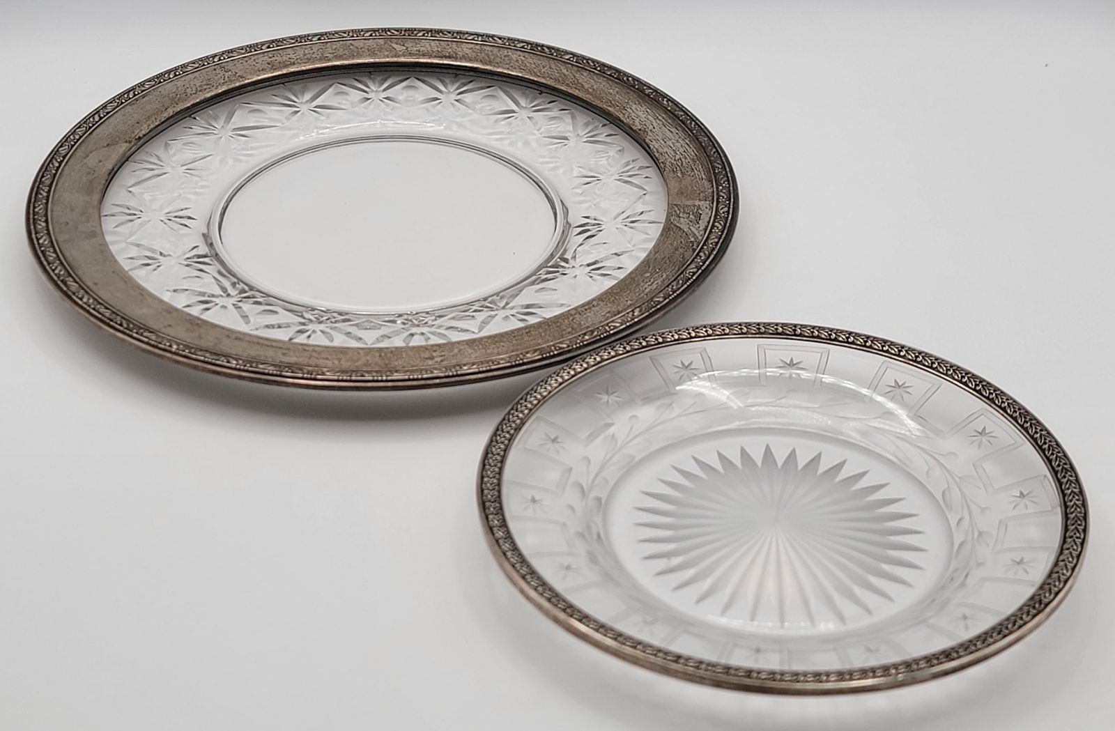 Two Sterling Silver Framed Etched Glass Plates: Two Sterling Silver Framed Etched Glass Plates. The larger plate is made by Wallace and measures 11" in diameter, the sterling frame measures 1-1/8" wide. The smaller plate measures 7-1/2" in diameter