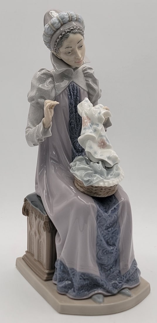 Retired Lladro "Sewing A Trousseau" Figurine #5126: Retired Lladro porcelain figurine titled "Sewing A Trousseau" #5126. The figurine has a gloss finish and is in great condition, signed on the base. Measures 11-1/2" tall x 4-3/8" across.