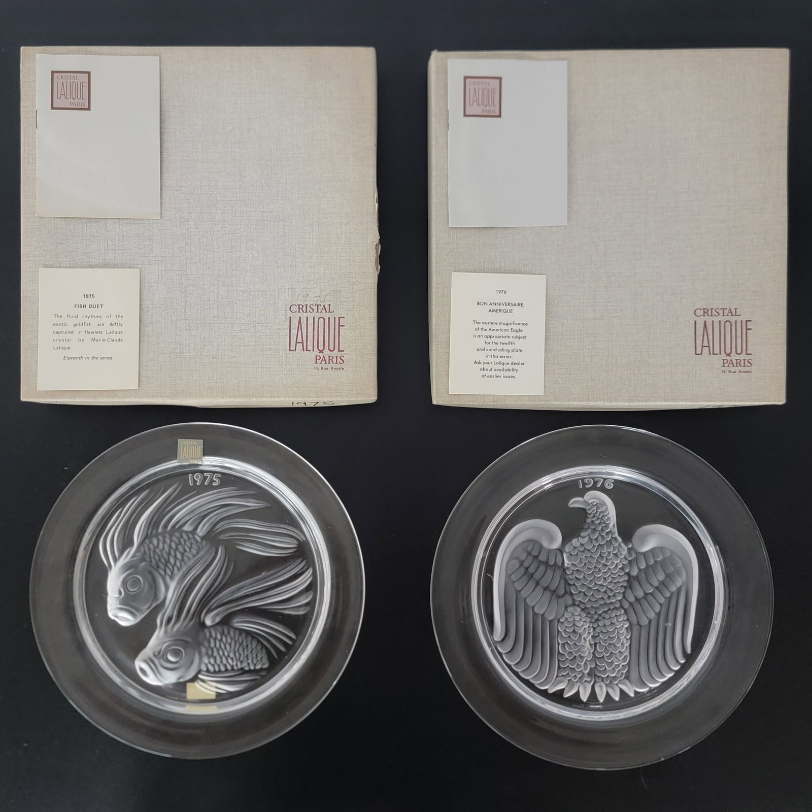 1975 & 1976 Lalique Crystal Annual Plates NIB: New In Box 1975 & 1976 Lalique Crystal Annual Plates. The 1975 is titled "Fish Duet" and the 1976 is titled "American Eagle". The plates are both signed and measure 8-1/4" in diameter. Designed by Mar