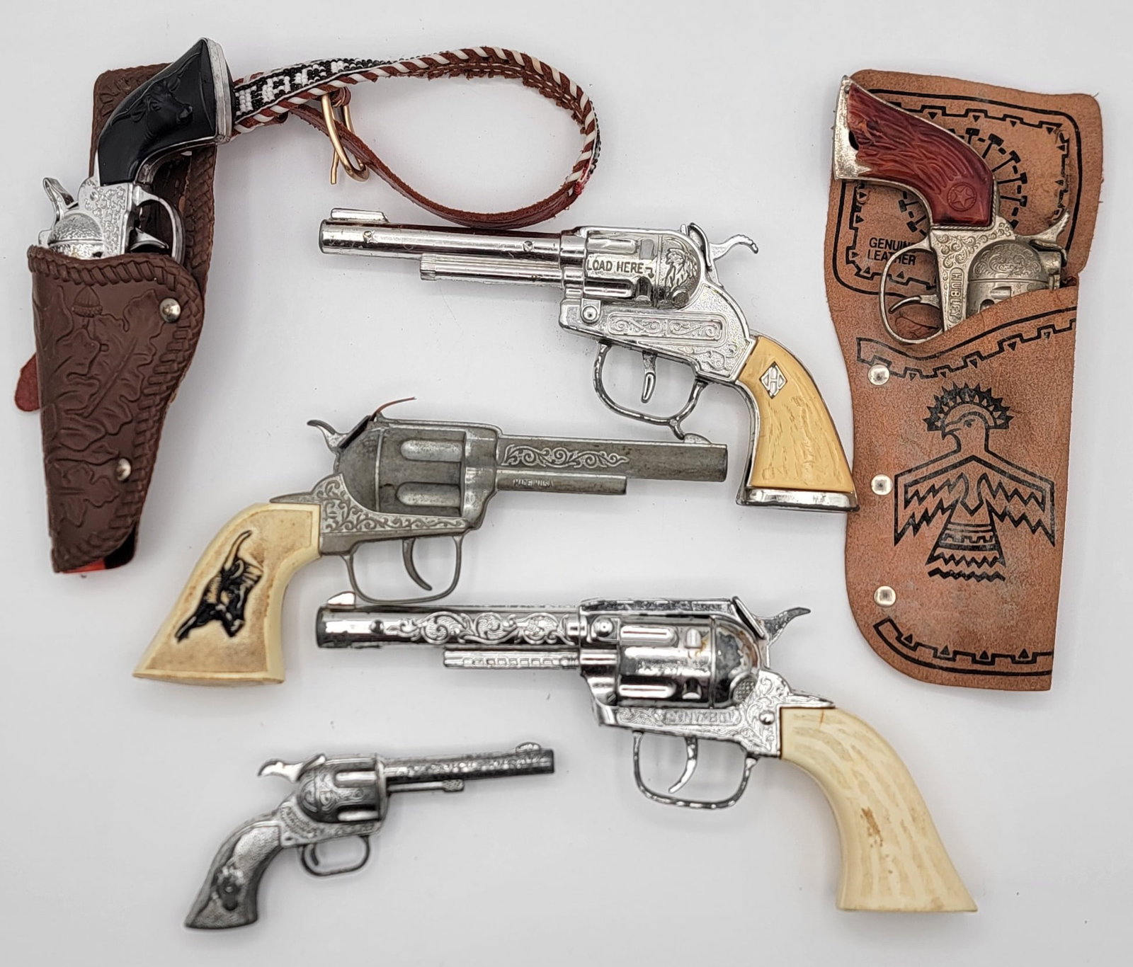 Lot Of Six Vintage Revolver Cap Guns: Lot Of Six Vintage Revolver Cap Guns. Lot includes Smoky, Pony Boy, Rodeo in holster, and more. Mixed conditions and the sizes range from 5-1/2" to 9-1/2" across.