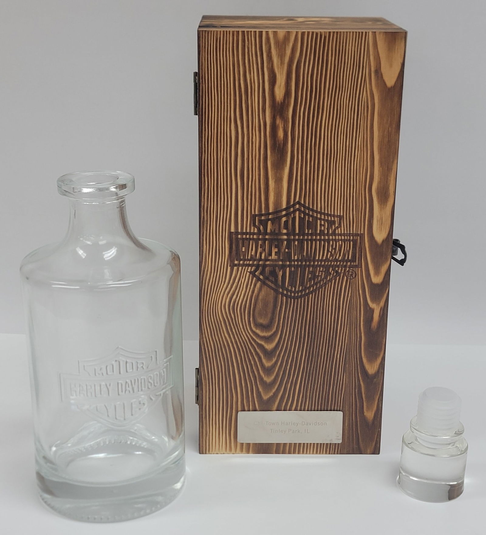 Harley-Davidson Glass Decanter In Wooden Box: Harley-Davidson Glass Decanter In Wooden Box. The decanter is in new unused condition and has a Chi-Town Harley-Davidson engraved plaque on the front of the wood box. Measures 10-1/2" tall. Comes in o