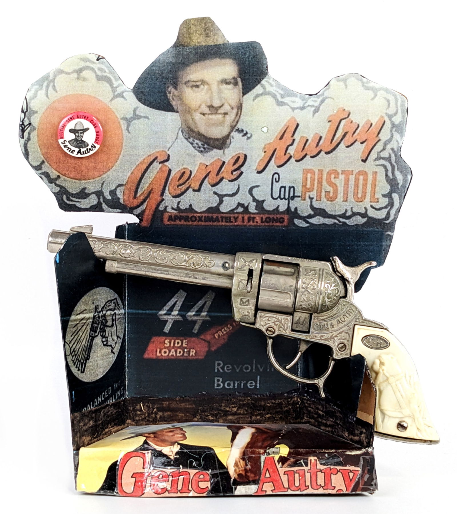 Leslie Henry Gene Autry 44 Cap Gun w/ Repo Display: Leslie Henry cap gun pistol with official Gene Autry club badge and reproduction cardboard display. When the trigger is pulled the cylinder rotates, but the hammer doesn't fire. The grips have a coupl