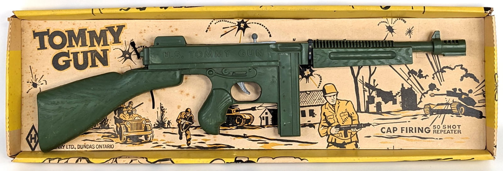 M.A. Henry Tommy Gun 50 Shot Repeater Cap Firing Gun In Box: M.A. Henry Tommy Gun 50 shot repeater cap firing gun in the original box. The box has some staining and wear from storage / age. The gun is new in the box. One of the zip ties on the gun has come undo