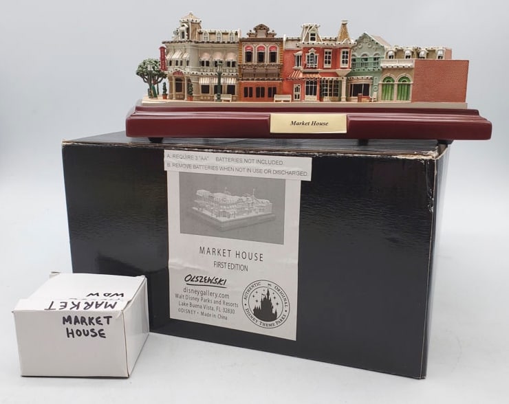 Disney Parks Olszewski First Edition Market House.: House Measures 10” Wide x 8 1/4” Deep x 3” High. House appears to be in overall good condition with flags taped to top of box with original box. Box appears to be in overall good con