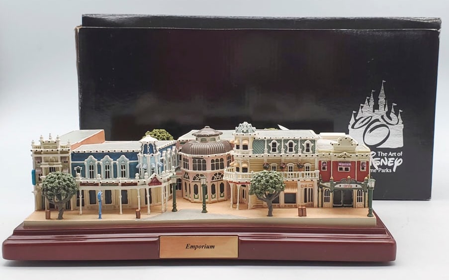 Disney Parks Olszewski First Edition Emporium: Emporium Measures 3 1/2” H x 10” W x 7” D. Emporium is in overall good condition with flags taped to top of building with overall good condition. With Box has some corner damage.