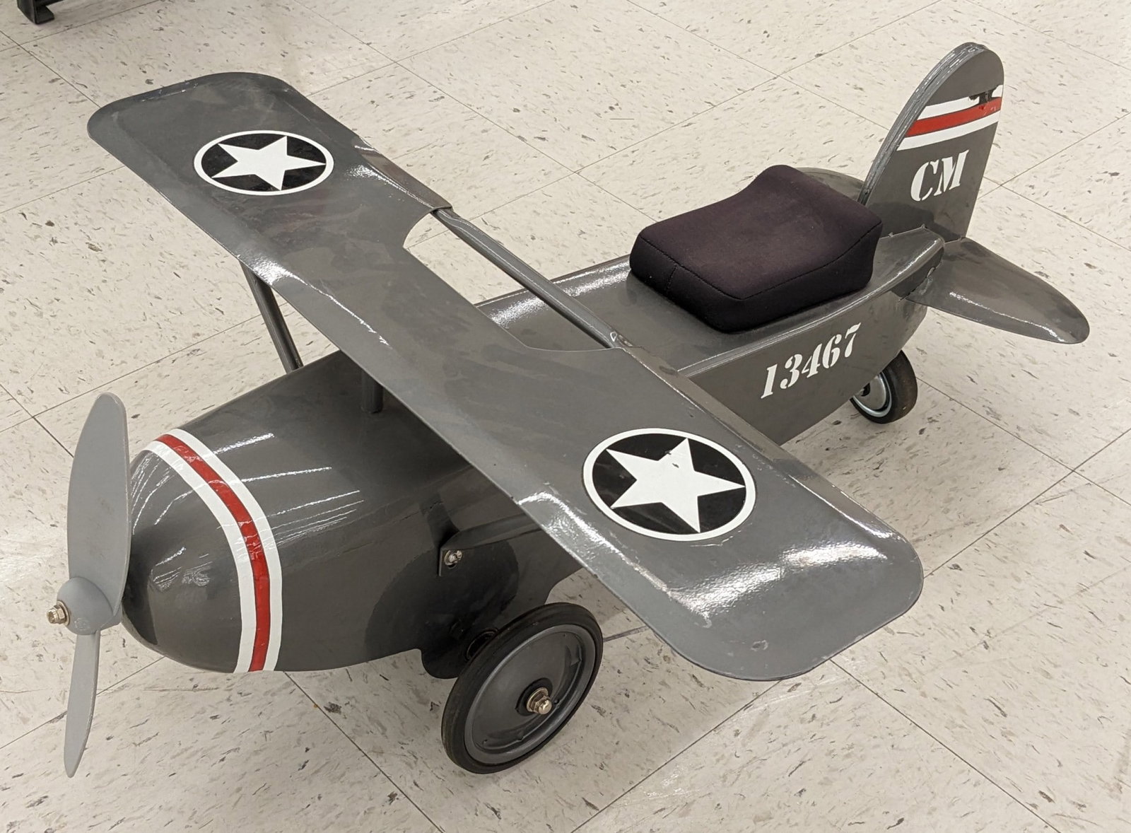 Contemporary Ride On Pressed Steel Plane: Contemporary pressed steel ride on airplane. Has some paint loss, decal loss, and wear from display and storage. Measures approximately 32in across by 27-1/2in wide.