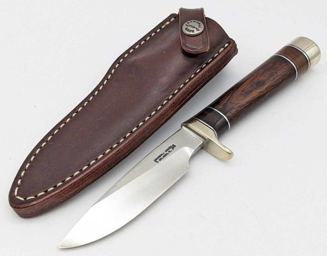 Randall Model 26 Pathfinder w/ Sheath: Knife features a stainless steel blade with thumb notches, nickel downturned single guard, Mexican desert ironwood handle with stacked leather spacers, and a nickel butt cap. Knife is in very nice con