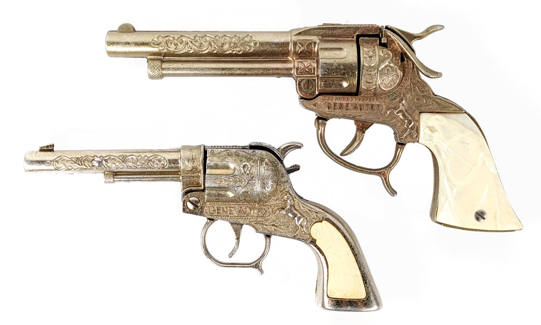 (2) Gold Gene Autry Cap Guns: Includes Leslie-Henry Gene Autry cap gun and Buzz-Henry cap gun. Both showing some color loss and wear from use / age. The Buzz-Henry trigger didn't function when pulled. Largest is approximately 9" l