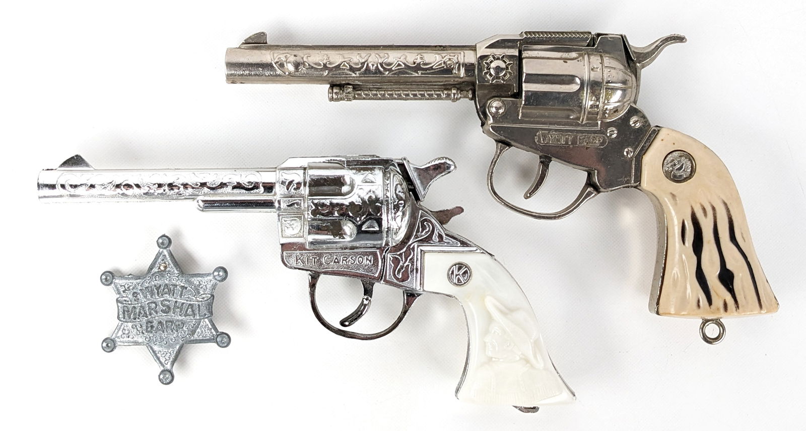 Wyatt Earp & Kit Carson Cap Guns: Includes Actoy Wyatt Earp cap gun with Wyatt Earp badge and Kilgore Kit Carson cap gun. The Kit Carson gun has some plate loss and the Wyatt Earp has some corrosion to the hammer. Largest measures 8-1