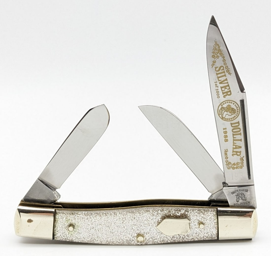 Ltd 1988 Frank Buster Fight'n Rooster Silver Dollar Silver Glitter Stockman: Knife is numbered 193 of 1000, and is in very nice condition with some tarnishing on the bolsters from handling. Overall measures 3-7/8in when closed.
