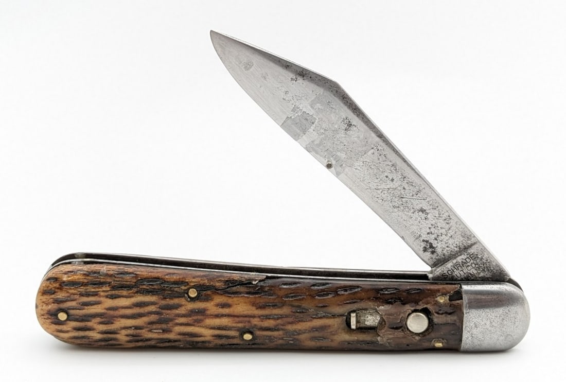 Schrade Cut Co Jigged Bone Press Button Switchblade Knife: Knife is in used condition with material loss and carbon spots on the blade, pitting and scratches on the bolsters, and worn handle scales with a repair around the push button, and a crack on the top