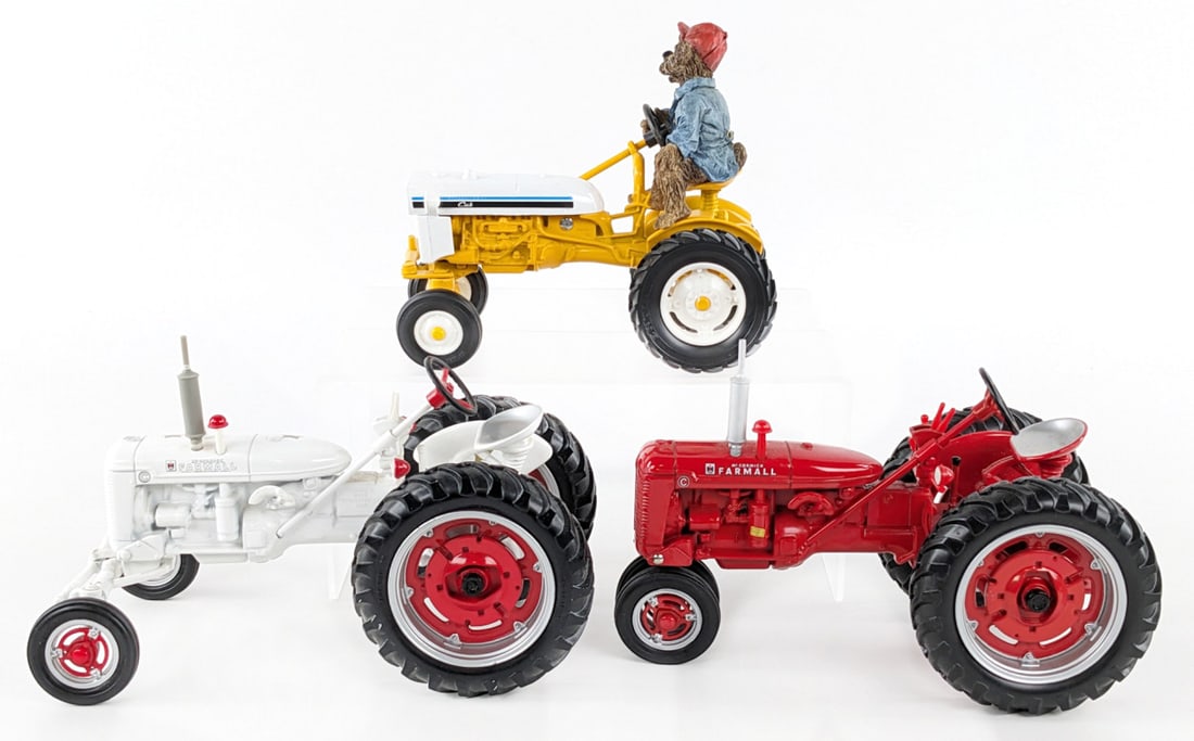1/16 Ertl Farmall C Tractors & International Cub: 1/16 Ertl Farmall C narrow front, Farmall C white demonstrator, and International Cub tractor with bear. All are in good condition with light dust from display.