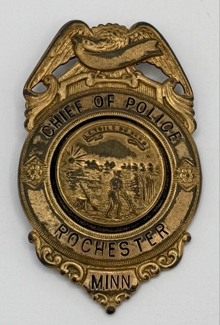 Obsolete Rochester Minnesota Chief Of Police Shield Badge: Obsolete Rochester Minnesota Chief Of Police Shield Badge. The gold-tone badge has a pin back, but is missing the clasp, has age and use wear. No maker mark. Badge measures approximately 2-3/4" tall b