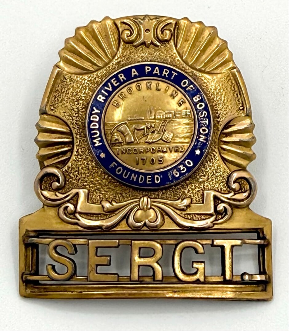 Obsolete Brookline Massachusetts Police Sergeant Hat Badge: Obsolete Brookline Massachusetts Police Sergeant Hat Badge. The gold-tone badge is in good condition with a screw back, has age and use wear. No maker mark. Badge measures approximately 2-1/4" tall by