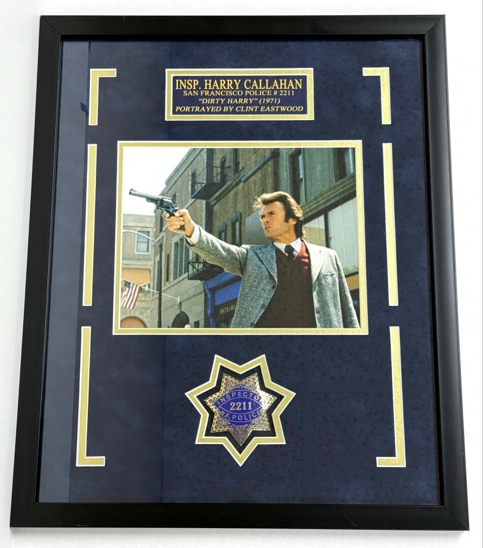 Framed & Matted Dirty Harry San Francisco Police Department Badge & Photo: Framed Insp. Harry Callahan "Dirty Harry" San Francisco Police Department Replica Badge #2211 with a photograph of Clint Eastwood. The badge and photo are framed and matted under glass. Overall the fr